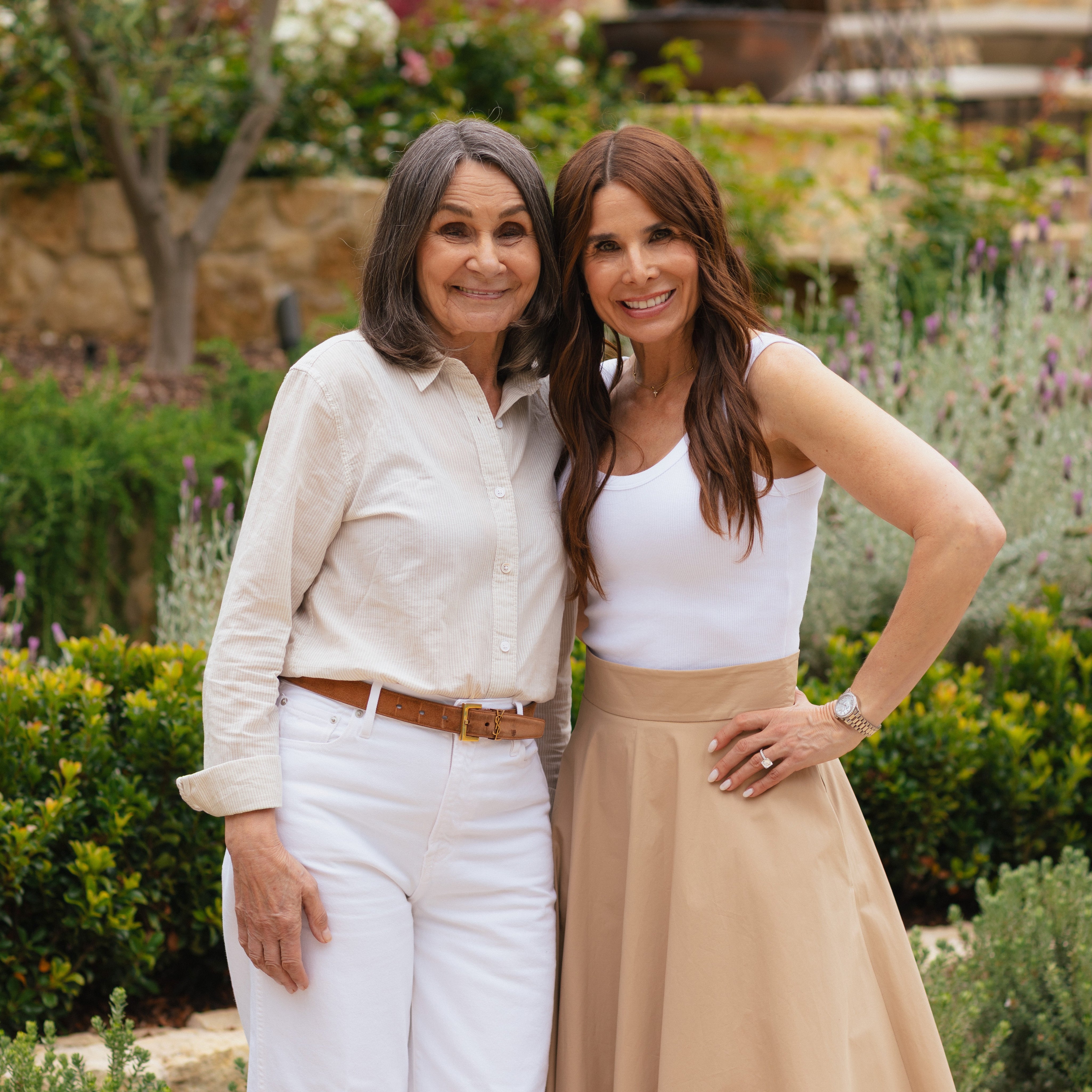 Two women standing together in a garden setting